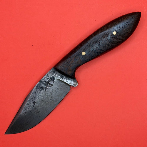 A handmade fixed-blade knife with a dark wood handle and a dark steel blade, shown diagonally on a solid red background.